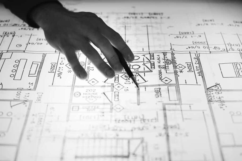 Photo of a hand over computer aided drafting plans pointing out parts of the duct design