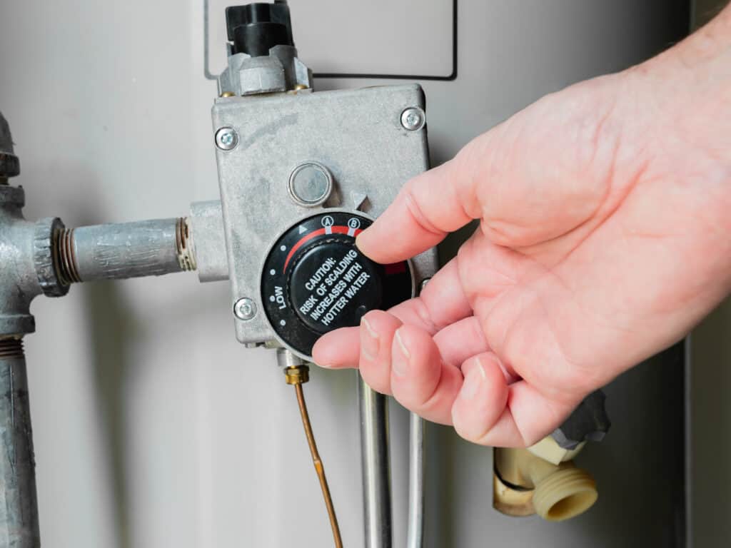 Plumber Adjusting Thermostat temperature dial on gas water heater