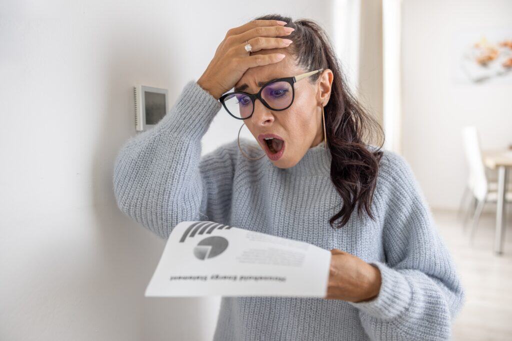 Woman holding energy bill looking Shocked From,The Rising Energy Costs and needing a replacement furnace
