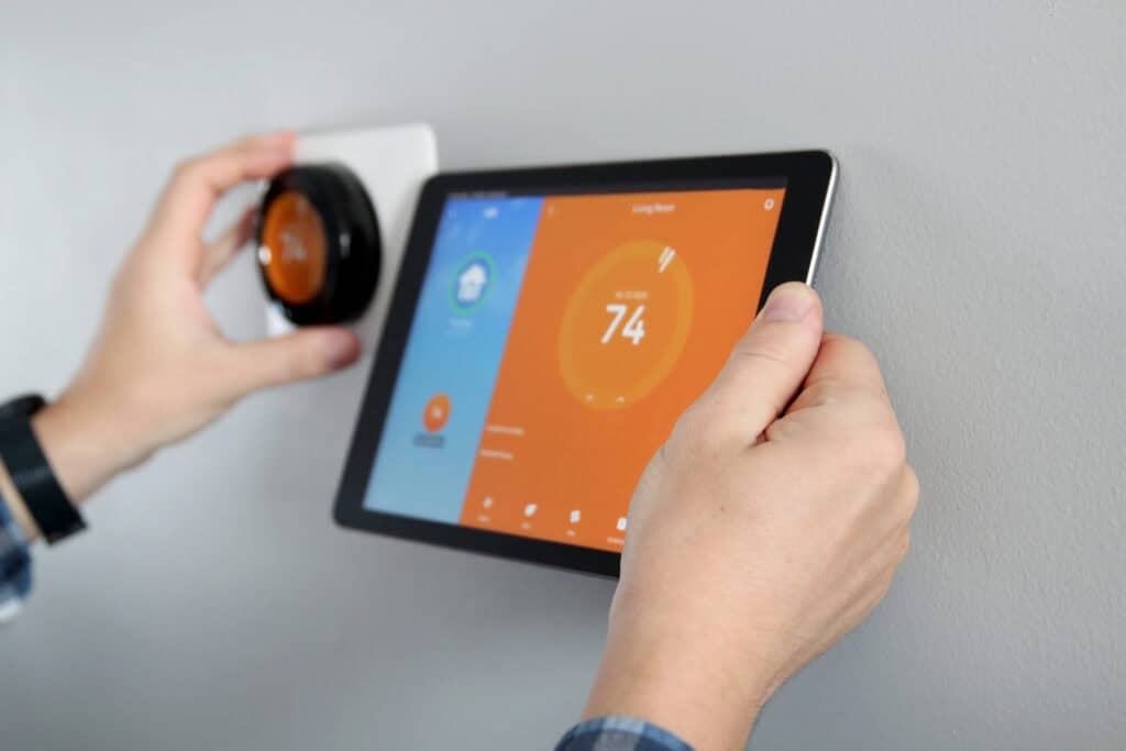 Man is Adjusting a temperature using a tablet with smart home app in modern living room