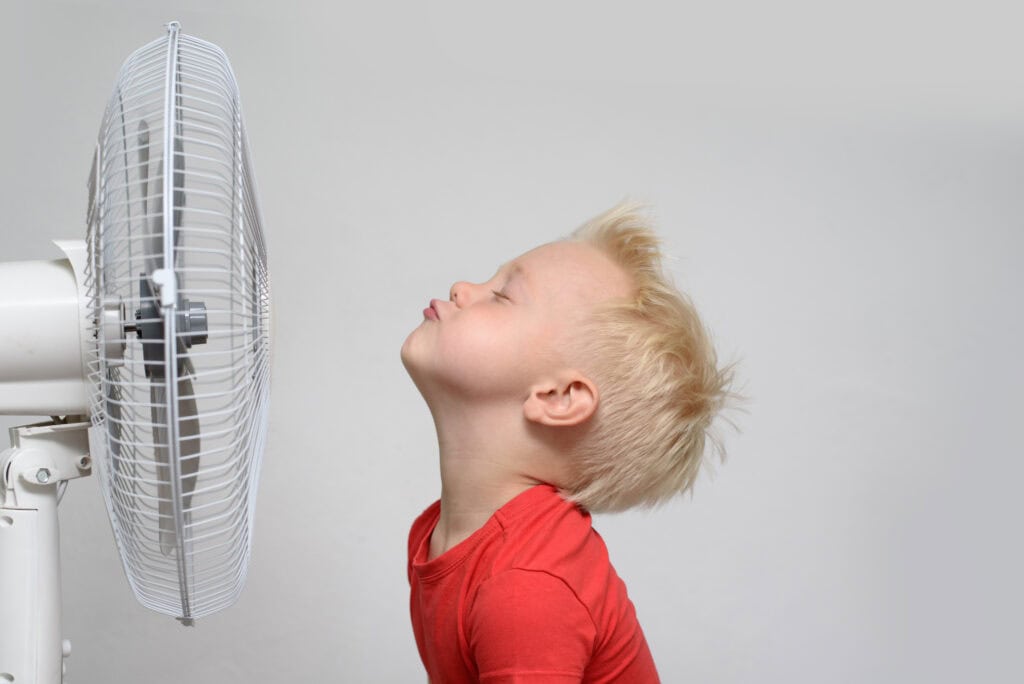 Smiling blond boy in red shirt and closed eyes enjoying the cool air. zoned AC concept